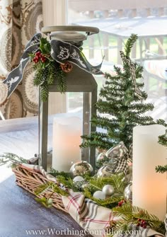 a table topped with candles next to a christmas tree and other decorations in front of a window