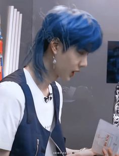 a man with blue hair and suspenders holding a piece of paper in his hand