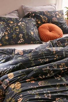 a bed with blue and orange floral comforter set on it's side next to a potted plant