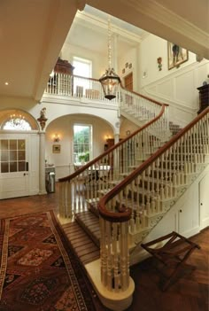 a staircase leading to the second floor in a large house with wood floors and white railings