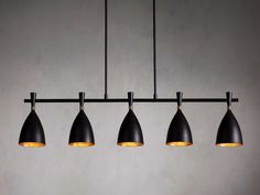 three black and gold lights hanging from a metal bar with four shades on each light