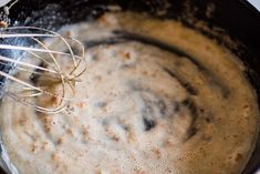 a whisk is being stirred in a black pot with brown liquid on it