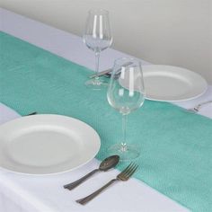 two empty wine glasses are sitting on a table with silverware next to it, along with plates and utensils