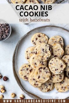 chocolate chip cookies with hazelnuts on a plate next to a bowl of nuts