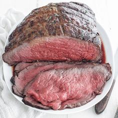 a large piece of meat on a plate with a knife and fork next to it