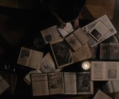 an overhead view of several open books on the floor with a candle in between them