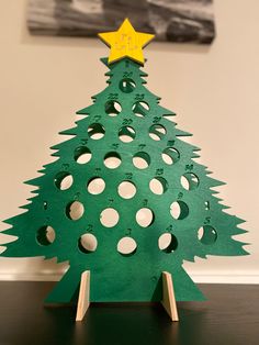 a wooden christmas tree with holes in the middle and a star on top, sitting on a table