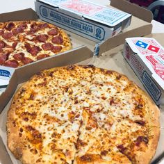 two pizzas sitting in boxes on top of a table