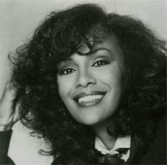 a black and white photo of a woman with long curly hair wearing a bow tie