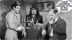 three men standing around a table with bottles and glasses on it, one man has a mustache