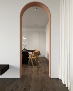 an arched doorway leads to a dining room with white walls and wood floors