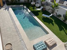 an aerial view of a swimming pool with lounge chairs and lawn area in the background