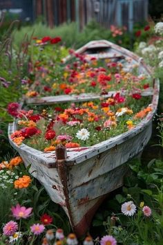 an old boat with flowers growing out of it's sides sits in the grass