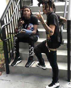 two young men sitting on steps with their hands in the air