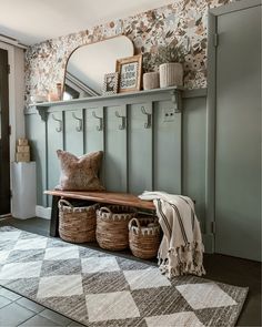 a bench with two baskets on it next to a wall mounted mirror and coat rack