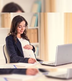 a pregnant woman sitting in front of a laptop computer while holding her belly and writing