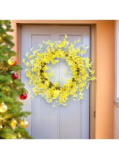 a yellow wreath hanging on the front door next to a christmas tree with ornaments around it