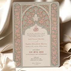 a wedding card with an ornate design on the front and back, sitting next to some flowers