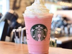 a pink starbucks drink sitting on top of a wooden table