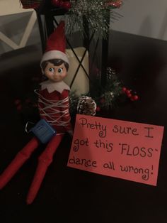 an elf is sitting next to a sign that says pretty sure i got this floss dance all wrong