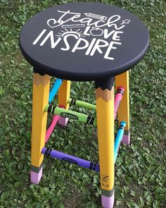 a stool made out of crayons in the grass with writing on it that says teach love inspire