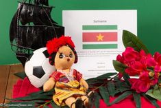 a stuffed doll sitting on top of a table next to flowers and a soccer ball