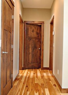 an empty hallway with wooden doors and hard wood flooring on either side of the door