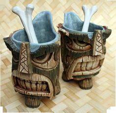 two wooden tiki style vases with spoons in them on a wood floor