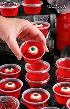 a person picking up some red cups with eyeballs on them