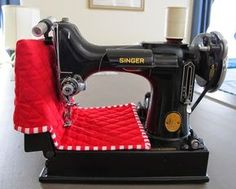 an old sewing machine with red and white fabric on it's foot rests on a table