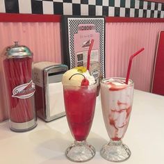 two drinks sitting on top of a table next to a blender and ice cream