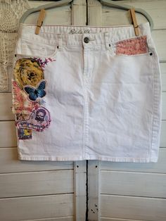 "Women's Eddie Bauer white denim mini-skirt, size 10.  Uniquely upcycled using t-shirt graphics and reclaimed, clean vintage fabrics.  All sewing is done by hand, including embroidery done as embellishment.  Waist is approximately 34\", length is approximately 18.5\"." White Cotton Mini Denim Skirt, Upcycled Cotton Denim Skirt, Upcycled Cotton Denim Skirt For Summer, Upholstery Fabric Remnants, Denim Upcycle, Floral Upholstery Fabric, Embellished Skirt, White Denim Skirt, Shirt Graphics