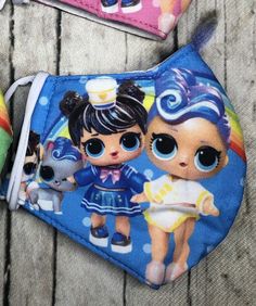 two purses with little dolls on them sitting next to each other in front of a wooden table