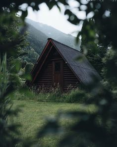 a log cabin nestled in the woods with mountains in the background