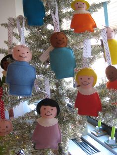 a christmas tree decorated with paper dolls hanging from it's branches