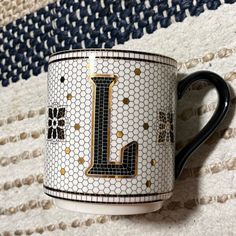 a black and white coffee cup with the letter l painted on it's side