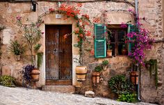 an old building with potted plants and flowers on the outside