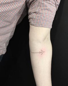 a small arrow tattoo on the arm