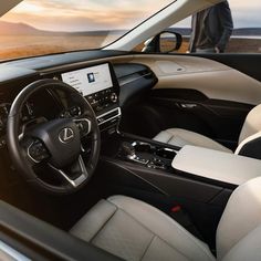 the interior of a modern car with white leather seats and dashboard, along with a man standing in the background