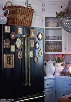 a black refrigerator with pictures on it in a kitchen