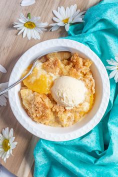 a bowl filled with ice cream next to daisies on a blue towel and white flowers