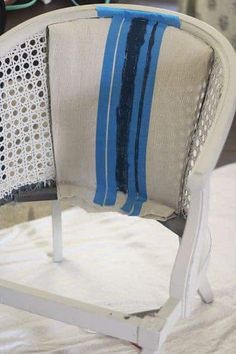 a white chair with blue and black striped fabric on it's armrests