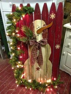 a wooden fence decorated with christmas lights and a snowman in the center is an ad for apartment com