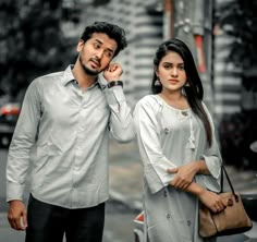 a man and woman standing next to each other on the street with cars in the background