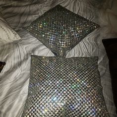 two shiny pillows sitting on top of a bed next to each other in front of a pillow