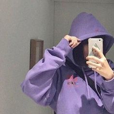 a person wearing a purple hoodie taking a selfie in the mirror with a cell phone