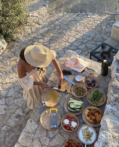 a woman in a straw hat is preparing food on the ground