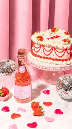 there is a cake, bottle and confetti on the table with pink decorations