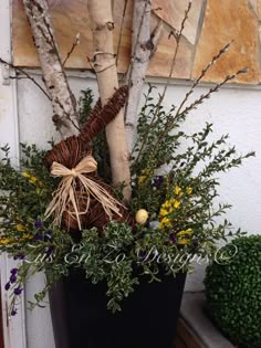 a planter filled with branches and flowers next to a wall