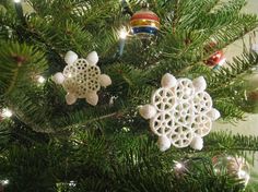 a christmas tree with ornaments hanging from it's branches in the shape of snowflakes